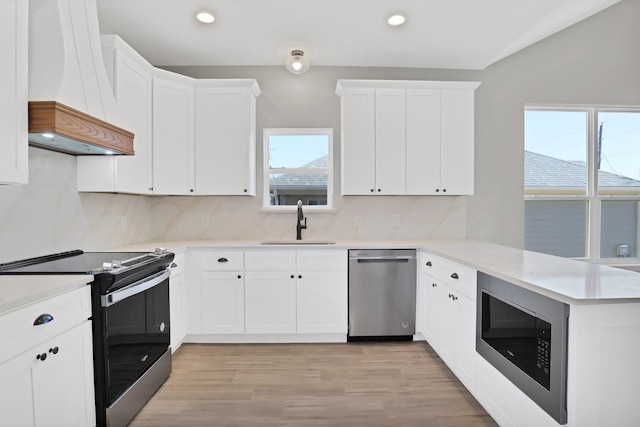 kitchen with sink, white cabinetry, stainless steel appliances, custom exhaust hood, and kitchen peninsula