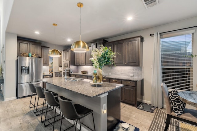 kitchen with hanging light fixtures, dark brown cabinets, stainless steel appliances, and sink