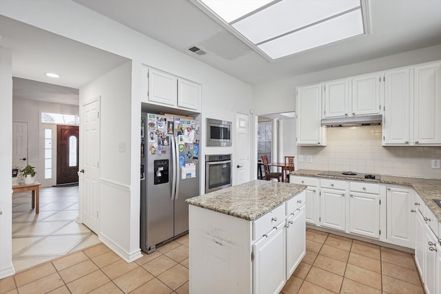 kitchen featuring light tile patterned floors, stainless steel appliances, tasteful backsplash, white cabinets, and a kitchen island