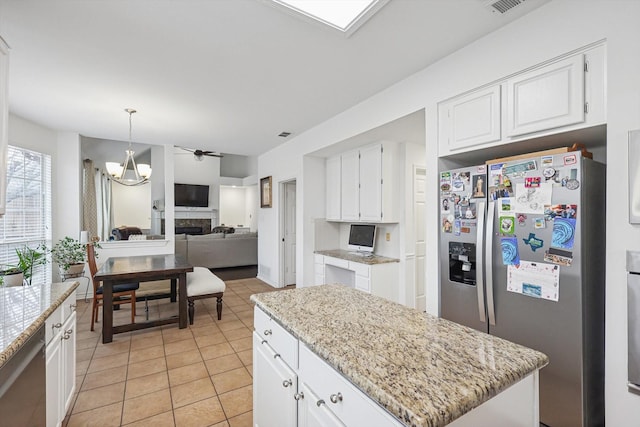 kitchen featuring light tile patterned flooring, a kitchen island, pendant lighting, stainless steel appliances, and white cabinets