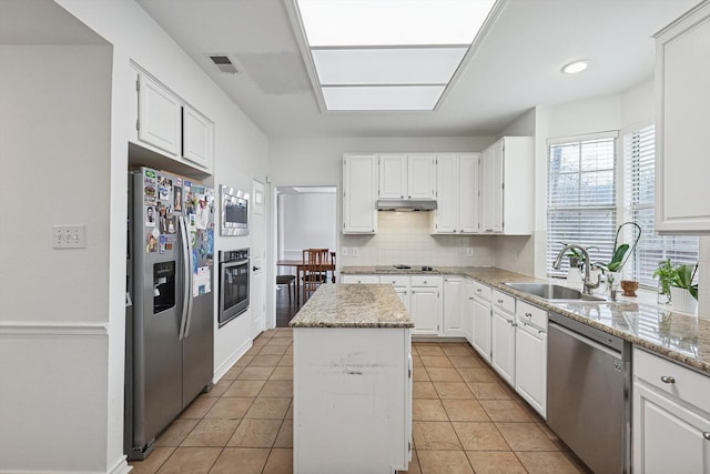 kitchen featuring a kitchen island, light stone countertops, white cabinets, and appliances with stainless steel finishes