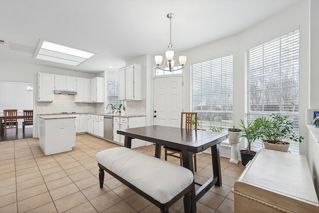 tiled dining room with sink, an inviting chandelier, and a skylight