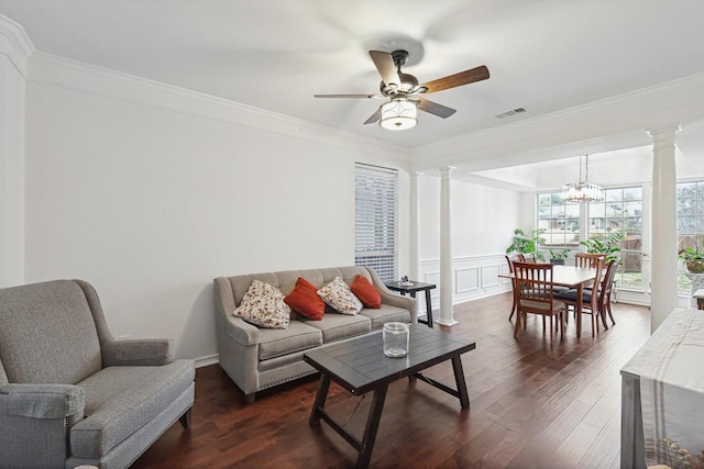 living room with crown molding, dark hardwood / wood-style floors, ceiling fan with notable chandelier, and decorative columns