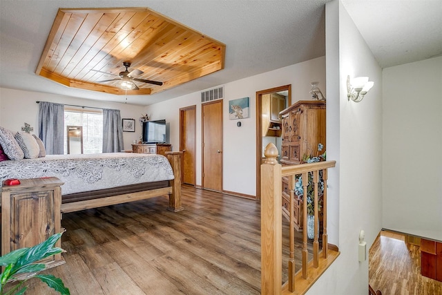 bedroom featuring a raised ceiling, hardwood / wood-style flooring, wooden ceiling, and ceiling fan