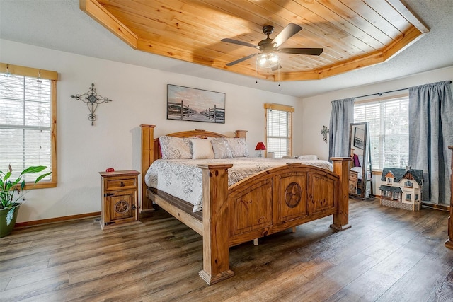 bedroom featuring dark wood-type flooring, wooden ceiling, ceiling fan, and a tray ceiling