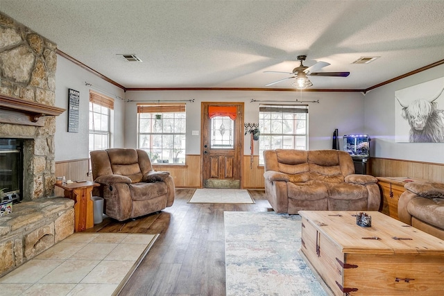 living room with crown molding, a textured ceiling, a fireplace, and a healthy amount of sunlight