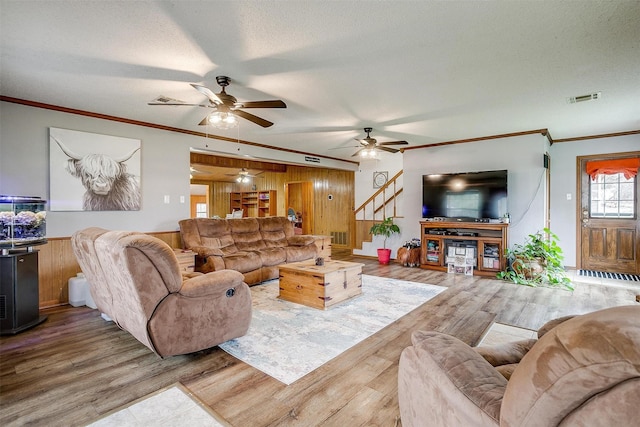 living room featuring ornamental molding, wooden walls, hardwood / wood-style floors, and a textured ceiling