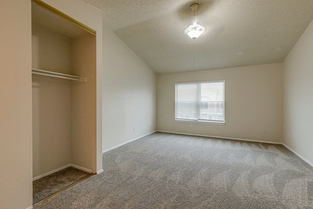 unfurnished bedroom with vaulted ceiling, a closet, a textured ceiling, and carpet flooring