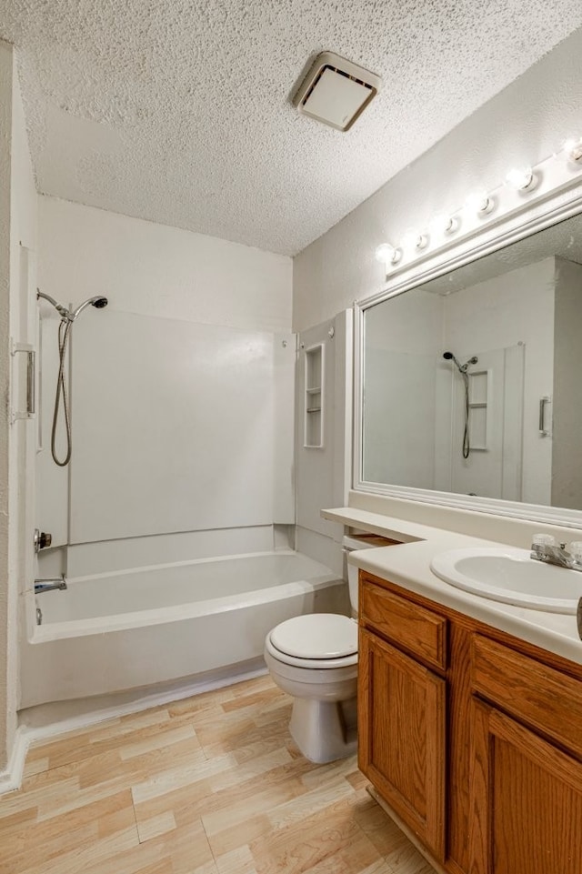 full bathroom with toilet,  shower combination, a textured ceiling, vanity, and hardwood / wood-style floors