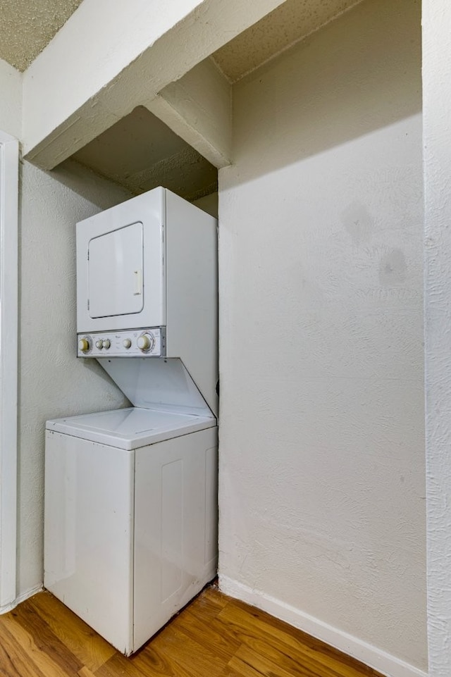 washroom with stacked washer and dryer and light wood-type flooring