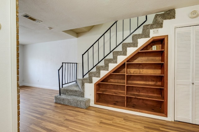 staircase with hardwood / wood-style flooring and a textured ceiling