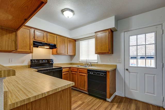 kitchen featuring sink, black appliances, a textured ceiling, kitchen peninsula, and light wood-type flooring