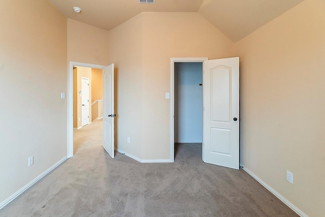 unfurnished bedroom featuring a walk in closet, light colored carpet, and high vaulted ceiling