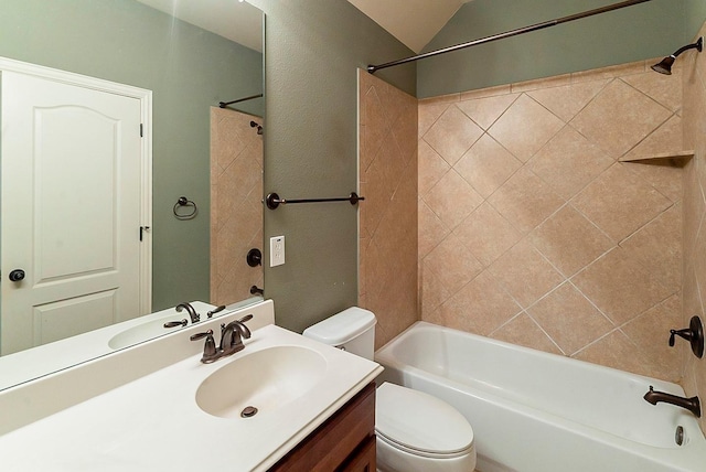 full bathroom featuring tiled shower / bath, lofted ceiling, vanity, and toilet