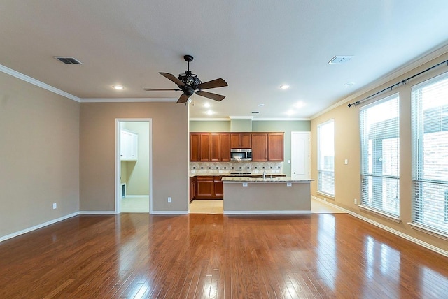 kitchen featuring crown molding, decorative backsplash, light hardwood / wood-style flooring, and plenty of natural light