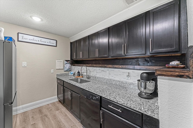 kitchen featuring sink, stainless steel refrigerator, black dishwasher, light hardwood / wood-style floors, and decorative backsplash