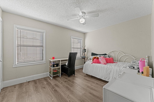 bedroom with ceiling fan, a textured ceiling, and light hardwood / wood-style flooring