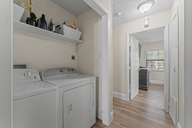 washroom with light hardwood / wood-style flooring, washing machine and dryer, and a textured ceiling