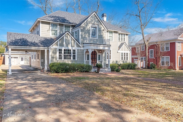 view of front of house with a front yard, roof with shingles, driveway, a chimney, and an outdoor structure