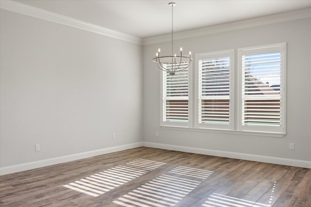 empty room with hardwood / wood-style flooring, crown molding, and a chandelier