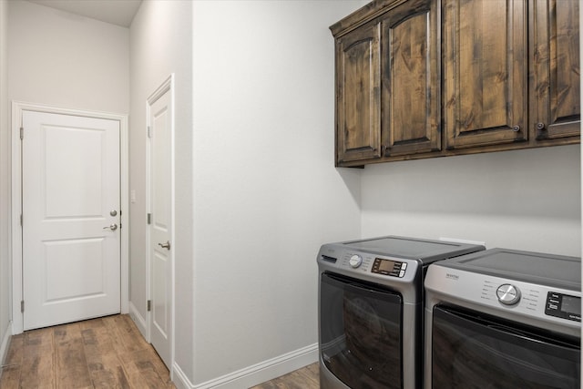 laundry area with cabinets, washing machine and clothes dryer, and hardwood / wood-style floors