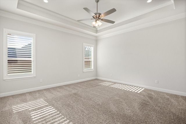 empty room with ornamental molding, a raised ceiling, ceiling fan, and carpet flooring