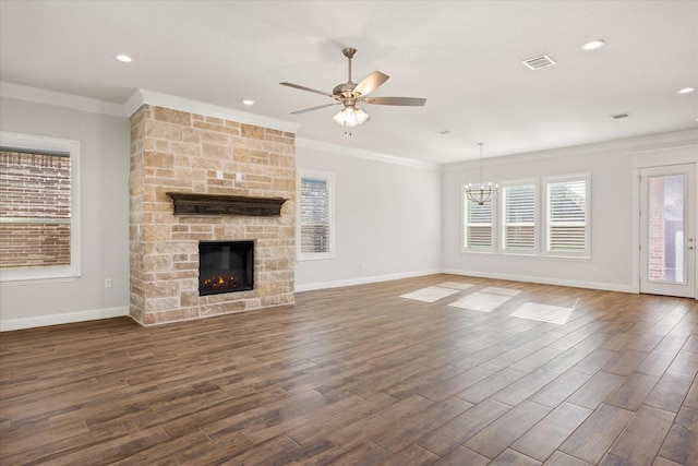 unfurnished living room featuring ornamental molding, dark hardwood / wood-style flooring, ceiling fan with notable chandelier, and a stone fireplace