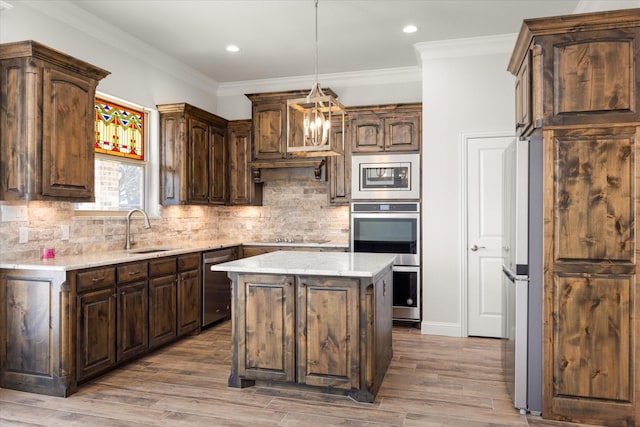 kitchen featuring dark brown cabinetry, sink, a center island, pendant lighting, and stainless steel appliances