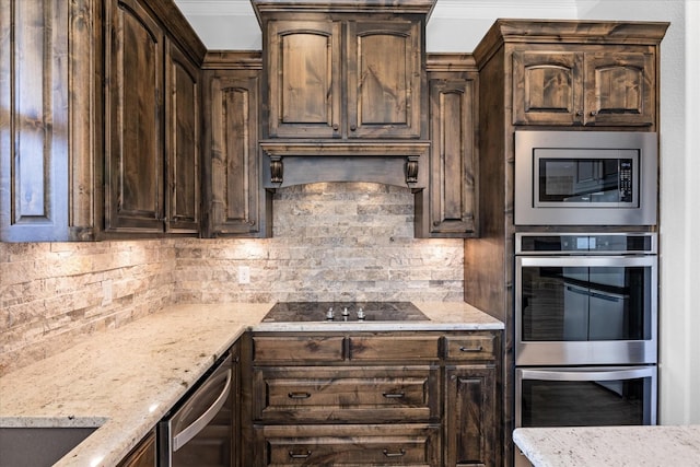 kitchen featuring appliances with stainless steel finishes, dark brown cabinets, light stone counters, and decorative backsplash