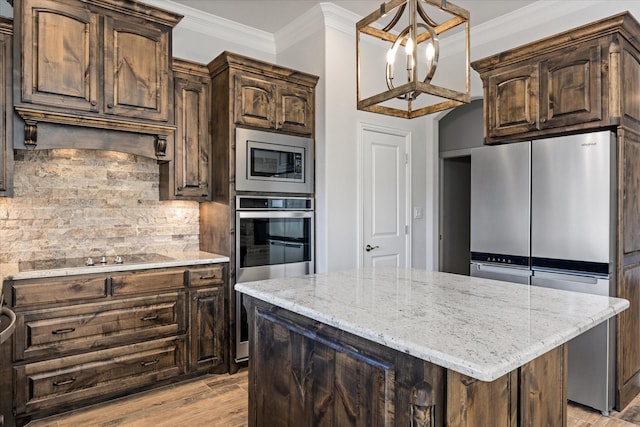 kitchen with stainless steel appliances, dark brown cabinetry, ornamental molding, light hardwood / wood-style floors, and a kitchen island