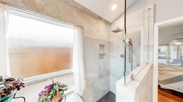 bathroom featuring hardwood / wood-style flooring, tiled shower, and lofted ceiling