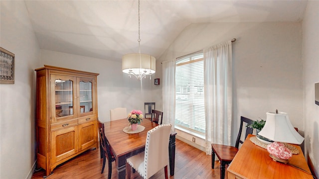 dining space featuring vaulted ceiling, an inviting chandelier, and light wood-type flooring