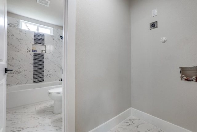 bathroom featuring tiled shower / bath combo and toilet