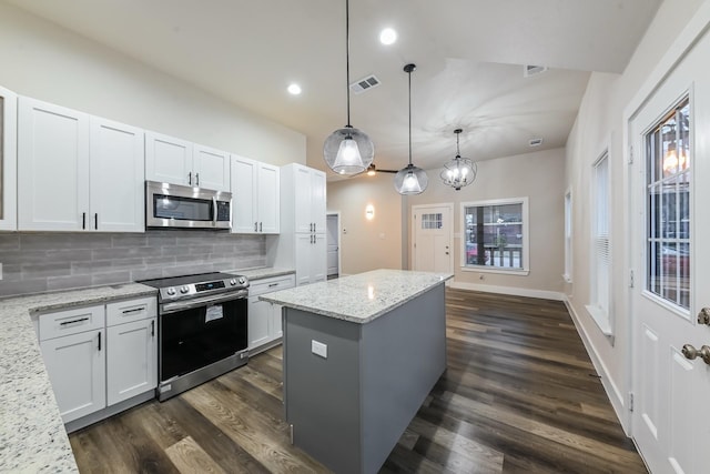 kitchen featuring appliances with stainless steel finishes, light stone countertops, hanging light fixtures, and white cabinets