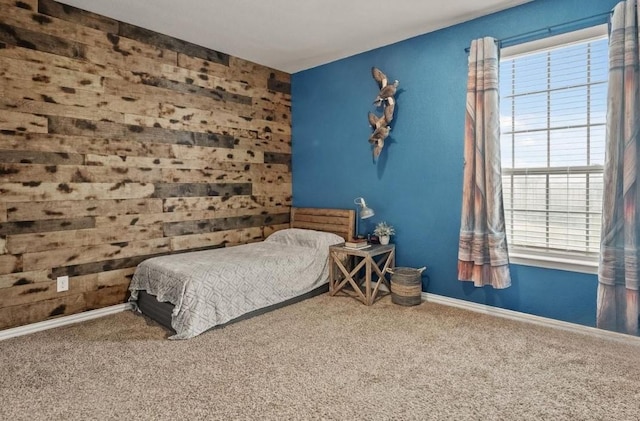 carpeted bedroom with an accent wall and baseboards