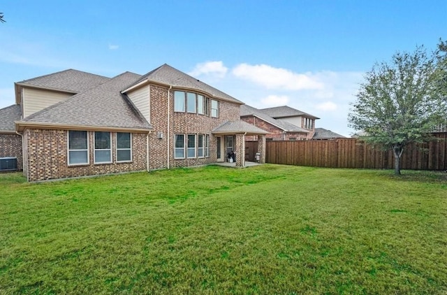 back of house featuring brick siding, a lawn, fence private yard, and a shingled roof