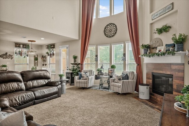 living room with dark wood-type flooring, a towering ceiling, plenty of natural light, and a fireplace