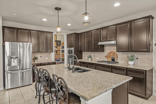 kitchen with stainless steel appliances, hanging light fixtures, sink, and a center island with sink