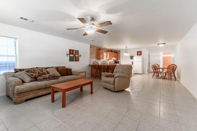 living room featuring light tile patterned flooring, plenty of natural light, a textured ceiling, and ceiling fan