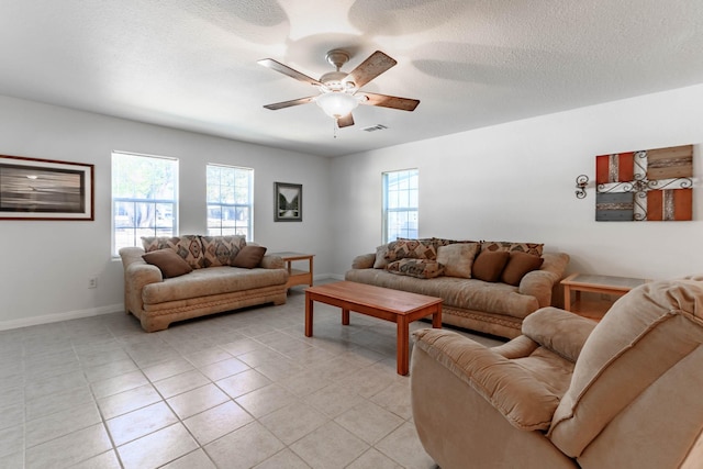 living room with light tile patterned flooring, ceiling fan, a healthy amount of sunlight, and a textured ceiling