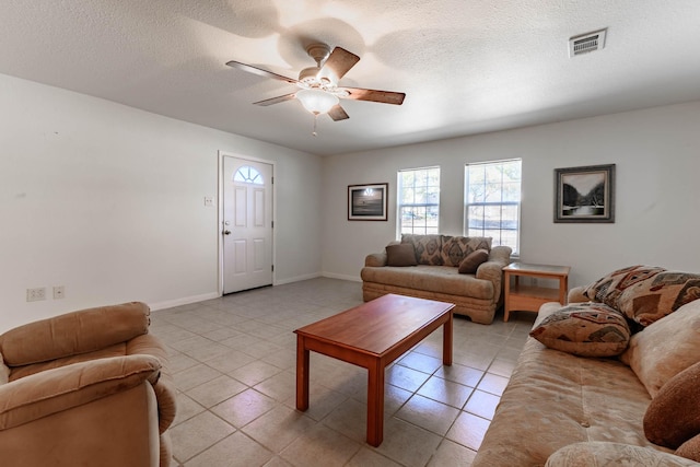 living room featuring light tile patterned flooring, ceiling fan, and a textured ceiling