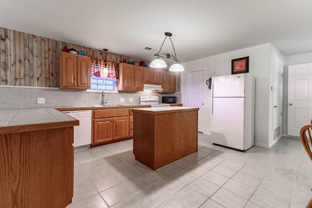 kitchen featuring pendant lighting, sink, backsplash, a center island, and white appliances