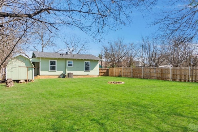 rear view of property with a lawn, a shed, and central air condition unit