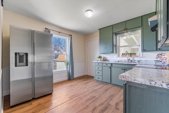 kitchen with stainless steel fridge, sink, and light hardwood / wood-style flooring