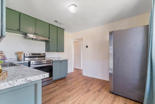 kitchen featuring sink, light hardwood / wood-style flooring, green cabinetry, and appliances with stainless steel finishes