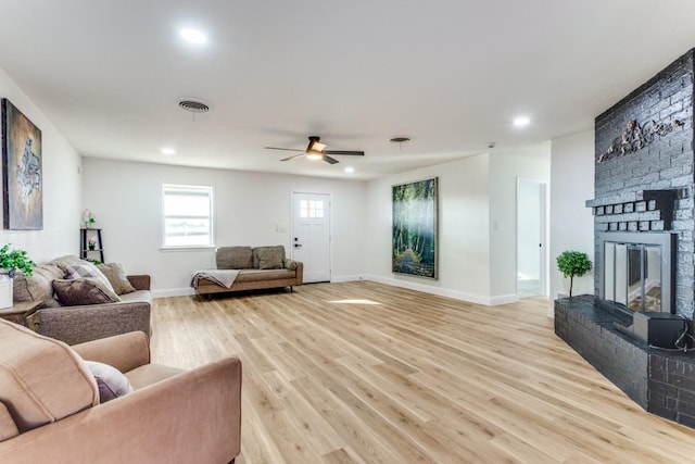 living room with ceiling fan, a fireplace, and light wood-type flooring