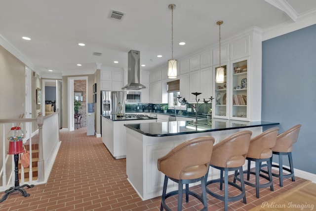 kitchen with appliances with stainless steel finishes, pendant lighting, white cabinetry, island exhaust hood, and crown molding