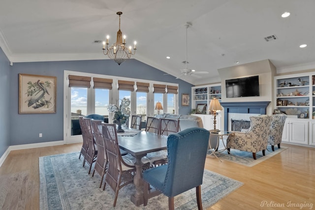 dining area featuring ornamental molding, ceiling fan with notable chandelier, vaulted ceiling, and light hardwood / wood-style floors