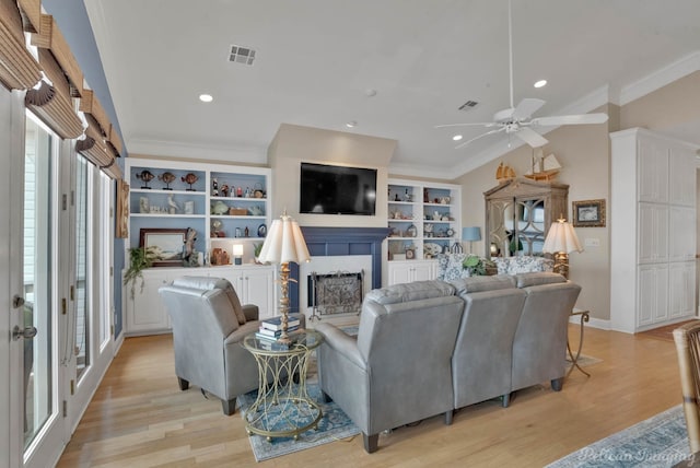 living room with ornamental molding, ceiling fan, and light wood-type flooring