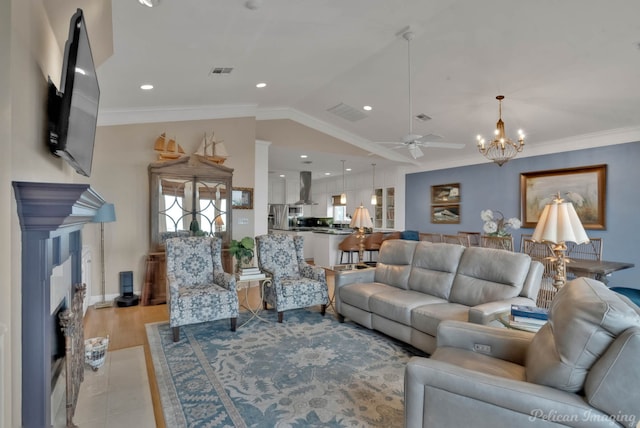 living room featuring lofted ceiling, ornamental molding, ceiling fan with notable chandelier, and light hardwood / wood-style flooring